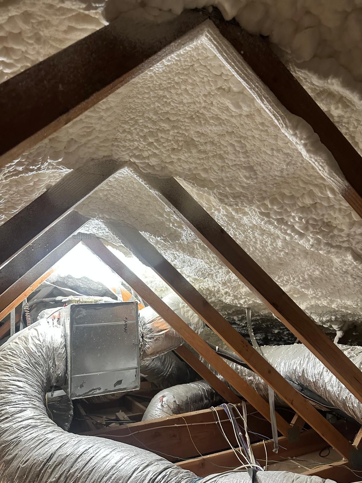 BW Insulation technician applying open-cell spray foam in an attic